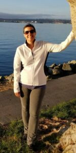 Lisa Burnside standing by a tree in front of a sidewalk by a lake